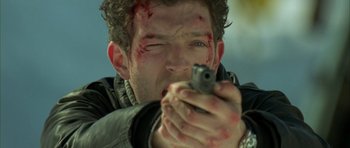 Movie still from “The Crimson Rivers” (2000), directed by Mathieu Kassovitz – A person holding a gun with blood all over his face; Close Up shot, Low angle