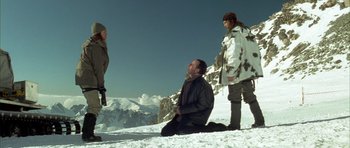 Movie still from “The Crimson Rivers” (2000), directed by Mathieu Kassovitz – A man kneeling on the ground in front of two other men; Wide shot, Low angle