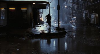 Movie still from “The Crow” (1994), directed by Alex Proyas – A man walking down the street in the rain at night; Extreme Wide shot, High angle