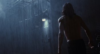 Movie still from “The Crow” (1994), directed by Alex Proyas – A man standing in the rain with his back to the camera; Wide shot, Low angle