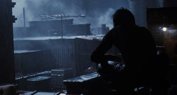 Movie still from “The Crow” (1994), directed by Alex Proyas – A man sitting on top of a wooden bench; Wide shot, High angle