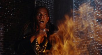 Movie still from “The Crow” (1994), directed by Alex Proyas – A man with dreadlocks is standing in front of a fire; Close Up shot, Low angle
