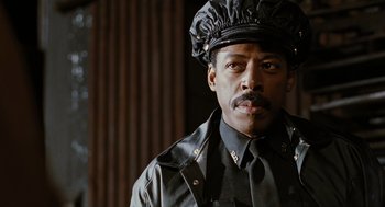 Movie still from “The Crow” (1994), directed by Alex Proyas – A man wearing a black hat and a black leather jacket; Close Up shot, Low angle