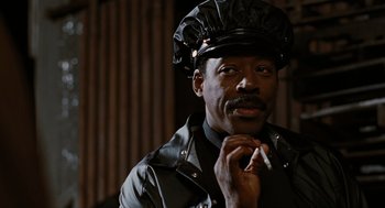 Movie still from “The Crow” (1994), directed by Alex Proyas – A man in a leather jacket and hat smoking a cigarette; Close Up shot, Low angle