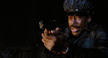 Movie still from “The Crow” (1994), directed by Alex Proyas – A man holding a gun in his hand; Close Up shot, Low angle