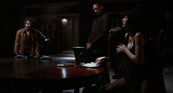 Movie still from “The Crow” (1994), directed by Alex Proyas – A group of people standing around a table; Medium shot, Over the shoulder angle