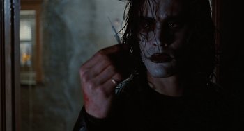 Movie still from “The Crow” (1994), directed by Alex Proyas – A person holding a knife in his hand; Close Up shot, Low angle