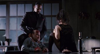 Movie still from “The Crow” (1994), directed by Alex Proyas – A group of men and women sitting around a table; Medium shot, Low angle