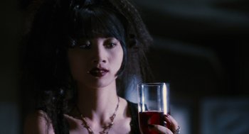 Movie still from “The Crow” (1994), directed by Alex Proyas – A woman holding a glass of red wine in her hand; Close Up shot, Low angle