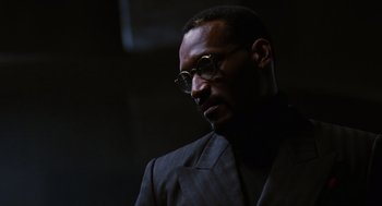Movie still from “The Crow” (1994), directed by Alex Proyas – A man in a suit and glasses is looking down; Close Up shot, Low angle