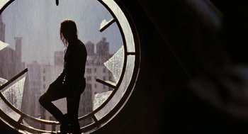 Movie still from “The Crow” (1994), directed by Alex Proyas – A woman standing in front of a large window; Wide shot, Low angle
