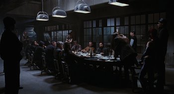 Movie still from “The Crow” (1994), directed by Alex Proyas – A group of people sitting around a table in a room; Wide shot, High angle