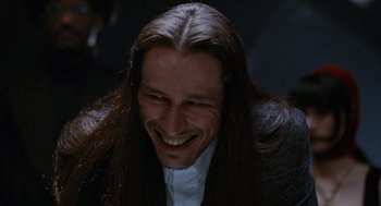 Movie still from “The Crow” (1994), directed by Alex Proyas – A person with long hair smiling; Close Up shot, Low angle