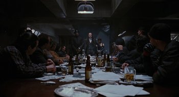 Movie still from “The Crow” (1994), directed by Alex Proyas – A group of people sitting around a table with drinks; Wide shot, High angle