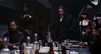 Movie still from “The Crow” (1994), directed by Alex Proyas – A man standing in front of a bunch of empty bottles; Medium shot, Over the shoulder angle