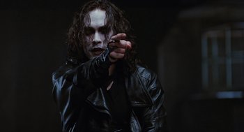 Movie still from “The Crow” (1994), directed by Alex Proyas – A person wearing a leather jacket; Medium shot, Low angle