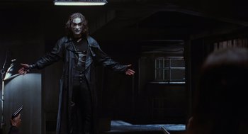 Movie still from “The Crow” (1994), directed by Alex Proyas – A man in a black coat and a black mask; Medium shot, Low angle