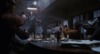 Movie still from “The Crow” (1994), directed by Alex Proyas – A group of people sitting at a table with drinks; Wide shot, Low angle