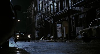 Movie still from “The Crow” (1994), directed by Alex Proyas – A car is parked on the side of the street; Wide shot, High angle