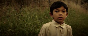 Movie still from “The Curse of La Llorona” (2019), directed by Michael Chaves – A young boy in a tan shirt standing next to a field; Close Up shot, Over the shoulder angle