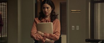 Movie still from “The Curse of La Llorona” (2019), directed by Michael Chaves – A woman holding a book while standing in front of a door; Medium shot, Over the shoulder angle