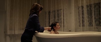 Movie still from “The Curse of La Llorona” (2019), directed by Michael Chaves – A young girl getting her hair washed in a bath tub; Medium shot, Over the shoulder angle