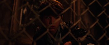 Movie still from “The Curse of La Llorona” (2019), directed by Michael Chaves – A young boy looking through a chain link fence; Close Up shot, High angle