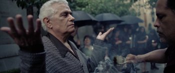 Movie still from “The Curse of La Llorona” (2019), directed by Michael Chaves – An older man standing in front of a group of people holding umbrellas; Close Up shot, Low angle