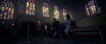 Movie still from “The Curse of La Llorona” (2019), directed by Michael Chaves – A man and a woman sitting in front of a stained glass window; Wide shot, Low angle