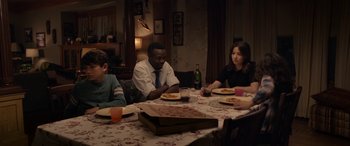 Movie still from “The Curse of La Llorona” (2019), directed by Michael Chaves – A group of people sitting around a table with pizza; Medium shot, High angle