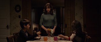 Movie still from “The Curse of La Llorona” (2019), directed by Michael Chaves – Three people sitting at a table with a plate of food; Medium shot, Over the shoulder angle
