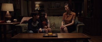 Movie still from “The Curse of La Llorona” (2019), directed by Michael Chaves – Three people sitting on a couch in a living room; Medium shot, High angle