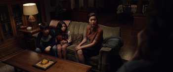 Movie still from “The Curse of La Llorona” (2019), directed by Michael Chaves – A woman sitting on top of a couch next to a little girl; Medium shot, High angle