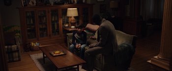 Movie still from “The Curse of La Llorona” (2019), directed by Michael Chaves – A man and a boy sitting on a couch in a living room; Medium shot, High angle