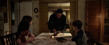 Movie still from “The Curse of La Llorona” (2019), directed by Michael Chaves – A man standing at a dinner table with candles; Medium shot, High angle