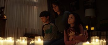 Movie still from “The Curse of La Llorona” (2019), directed by Michael Chaves – A woman and two children sitting in front of a lit candle; Medium shot, Low angle