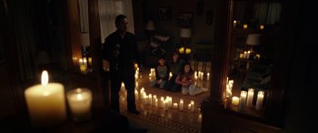 Movie still from “The Curse of La Llorona” (2019), directed by Michael Chaves – A group of people sitting in a living room with candles; Wide shot, High angle