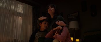 Movie still from “The Curse of La Llorona” (2019), directed by Michael Chaves – A woman and two boys are hugging in a room; Medium shot, Low angle