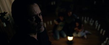 Movie still from “The Curse of La Llorona” (2019), directed by Michael Chaves – A man sitting on the floor in a dark room; Medium shot, Over the shoulder angle