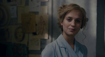 Movie still from “The Danish Girl” (2015), directed by Tom Hooper – A woman in a lab coat standing next to a wall; Close Up shot, Over the shoulder angle
