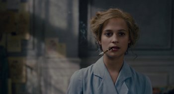 Movie still from “The Danish Girl” (2015), directed by Tom Hooper – A woman smoking a cigarette while wearing a blue suit; Close Up shot, Over the shoulder angle