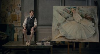 Movie still from “The Danish Girl” (2015), directed by Tom Hooper – A man sitting in front of a painting of a woman; Wide shot, Over the shoulder angle