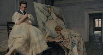 Movie still from “The Danish Girl” (2015), directed by Tom Hooper – Two women are painting a painting of a woman; Medium shot, Low angle