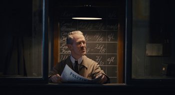 Movie still from “The Danish Girl” (2015), directed by Tom Hooper – A man in a suit and tie holding a newspaper; Medium shot, Low angle