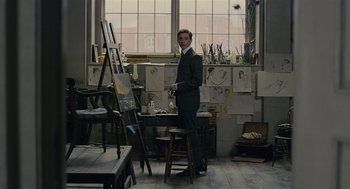 Movie still from “The Danish Girl” (2015), directed by Tom Hooper – A man standing in front of an easel in an art studio; Medium shot, High angle