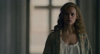 Movie still from “The Danish Girl” (2015), directed by Tom Hooper – A woman in a white shirt and a brown jacket looking sad; Close Up shot, Over the shoulder angle
