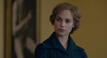 Movie still from “The Danish Girl” (2015), directed by Tom Hooper – A young woman in a blue coat looking at the camera; Close Up shot, Over the shoulder angle