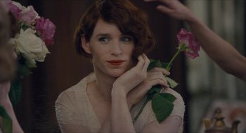 Movie still from “The Danish Girl” (2015), directed by Tom Hooper – A woman holding a pink flower in her hand; Close Up shot, Over the shoulder angle