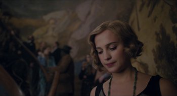 Movie still from “The Danish Girl” (2015), directed by Tom Hooper – A young woman with blonde curly hair and a green necklace; Close Up shot, Over the shoulder angle