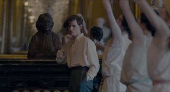 Movie still from “The Danish Girl” (2015), directed by Tom Hooper – A man standing in front of a mirror in front of a bust; Medium shot, Over the shoulder angle
